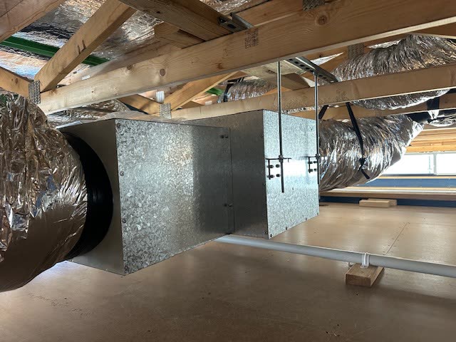 Daikin premium ducted unit hung under the roof trusses, insulated flexible ducts running off it.